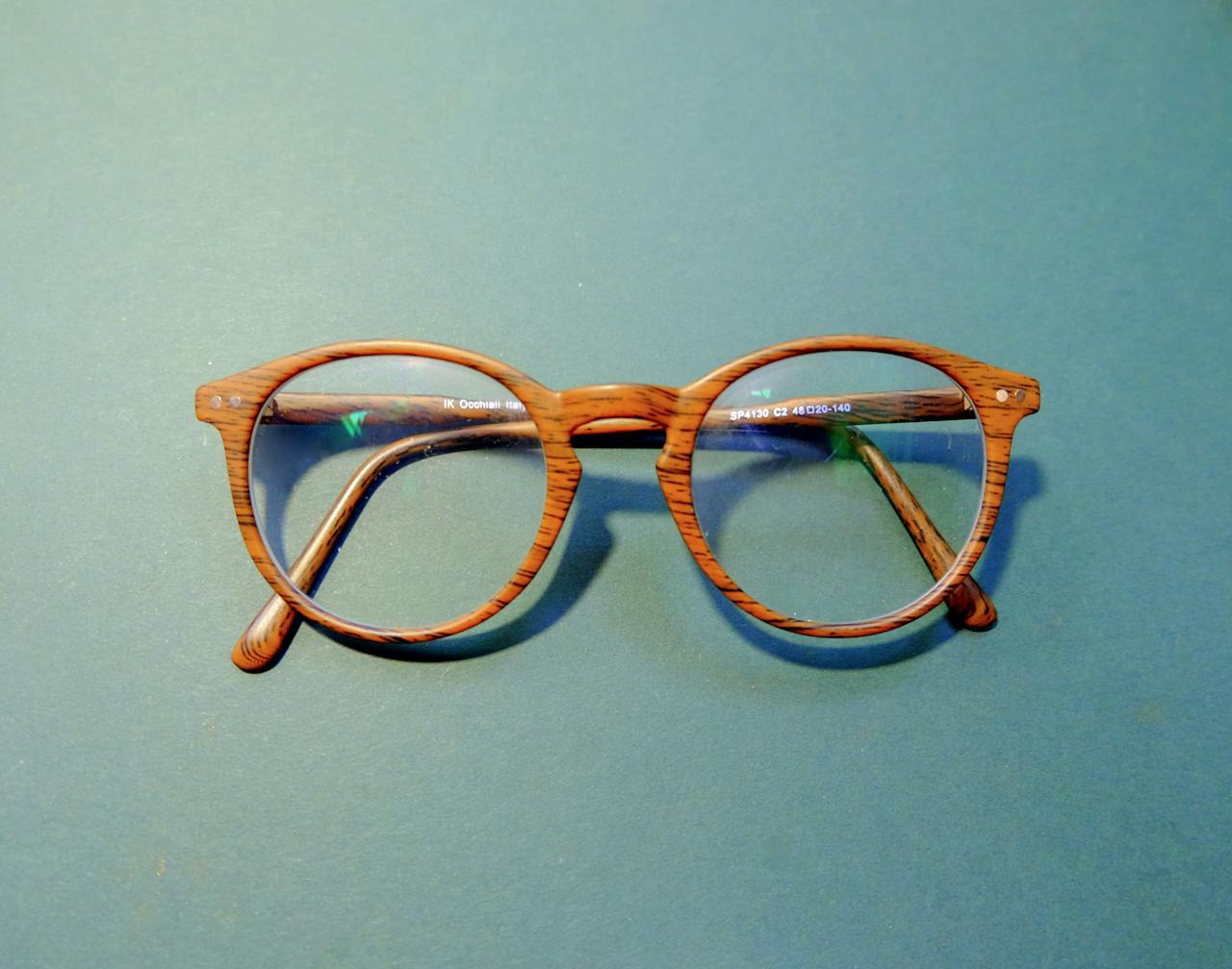The Art of Drawing Readers In: Your attractive post title goes here Close-up of fashionable wooden frame eyeglasses on a solid blue background.